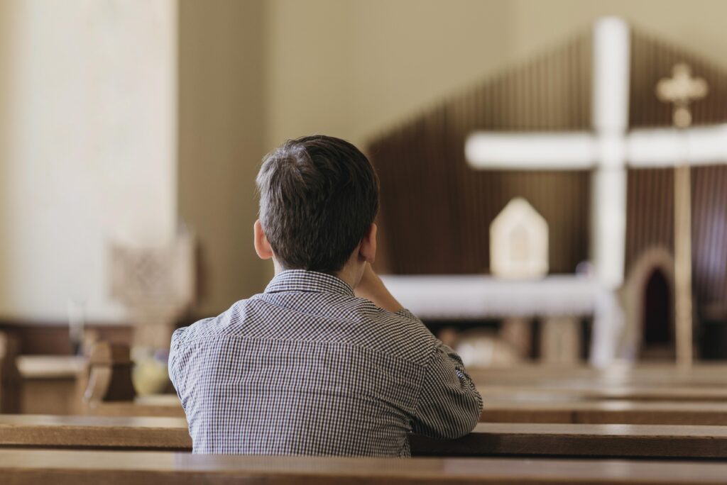 back view young boy praying in the church scaled
